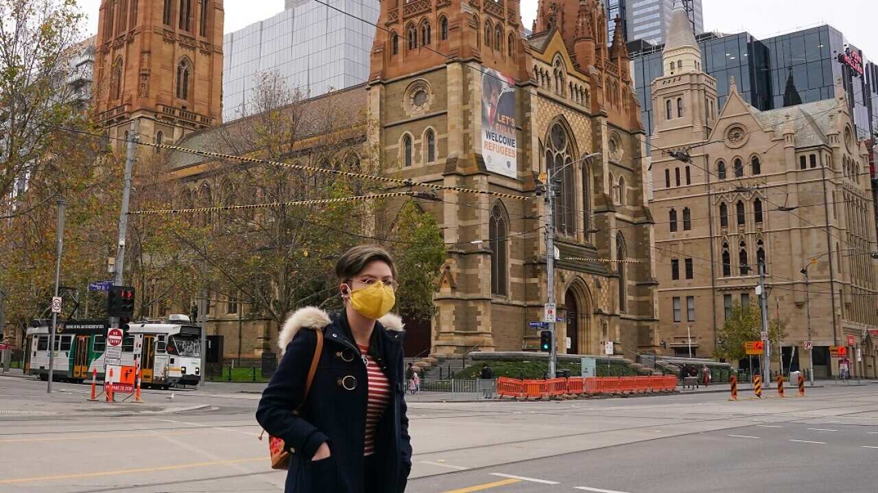 A woman walks past St Paul's Cathedral while wearing a face.