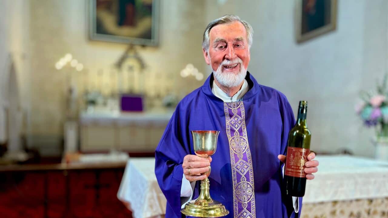 Father Brendan Kelly, Superior at Sevenhill Jesuit Mission in South Australia, holding sacramental wine which is still made on site, as it has been for 175 years. (SBS -Lloyd Thornton).jpg