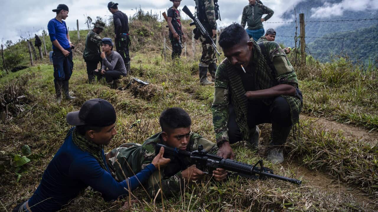 Two members of the old Revolutionary Armed Forces of Colombia, known as the FARC, teach a new FARC member how to use his assault rifle at a shooting camp, in mountains north of Medelln, Colombia.