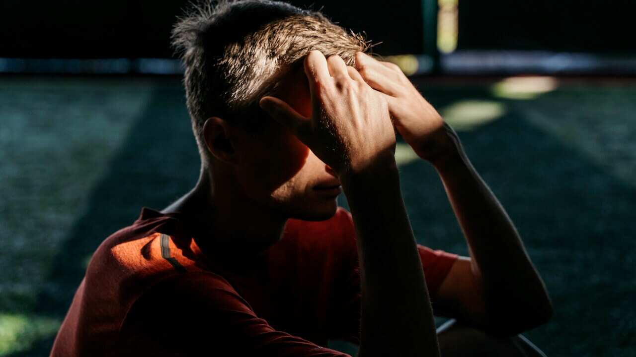 Mid adult man in sunbeam in dark. Depression concept.