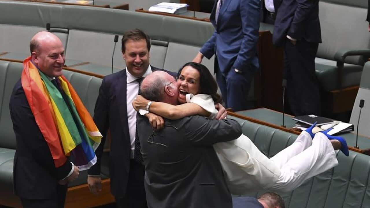 Liberal MP Warren Entsch lifts Labor MP Linda Burney in celebration.