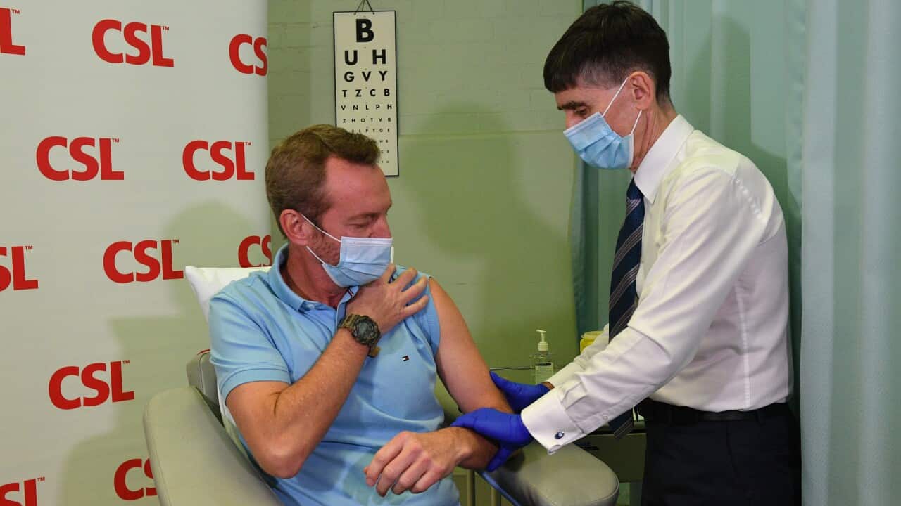 Dr Tony Bartone (right), prepares to administer a locally manufactured AstraZeneca vaccine at CSL in Melbourne.