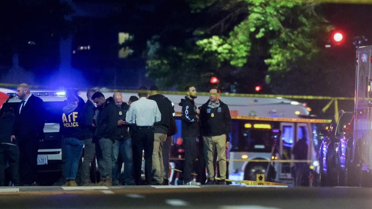 Police standing at a crime scene, blocked off by yellow police tape.