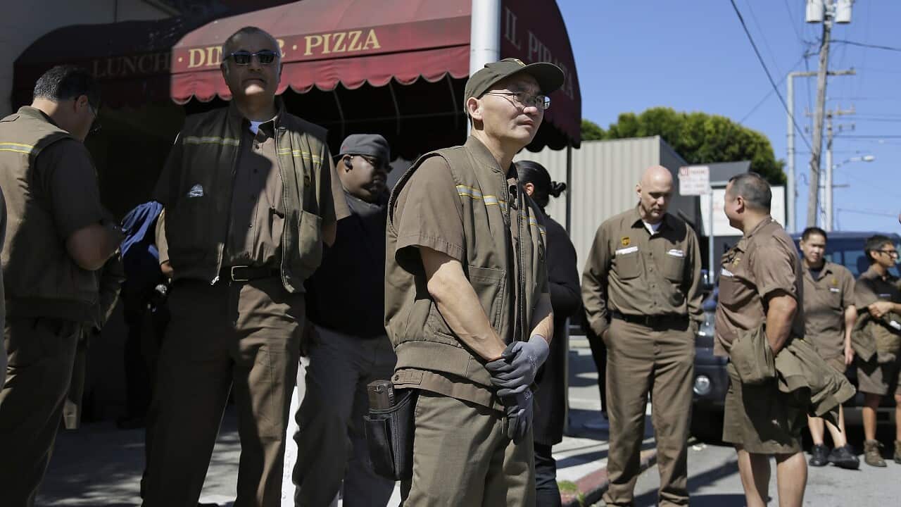 UPS workers gather outside a UPS package delivery warehouse where a shooting took place in San Francisco.