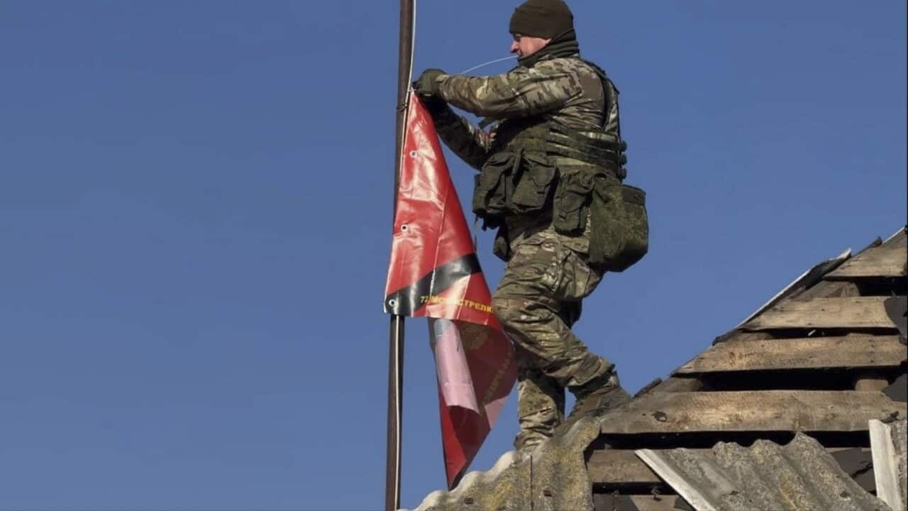 A Russian soldier raises a flag atop a house in the Kursk region (AAP)