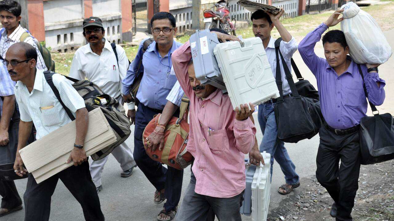 Indian poll officials carry Electronic Voting Machines (EVM) from a distribution centre in Tezpur (AAP)