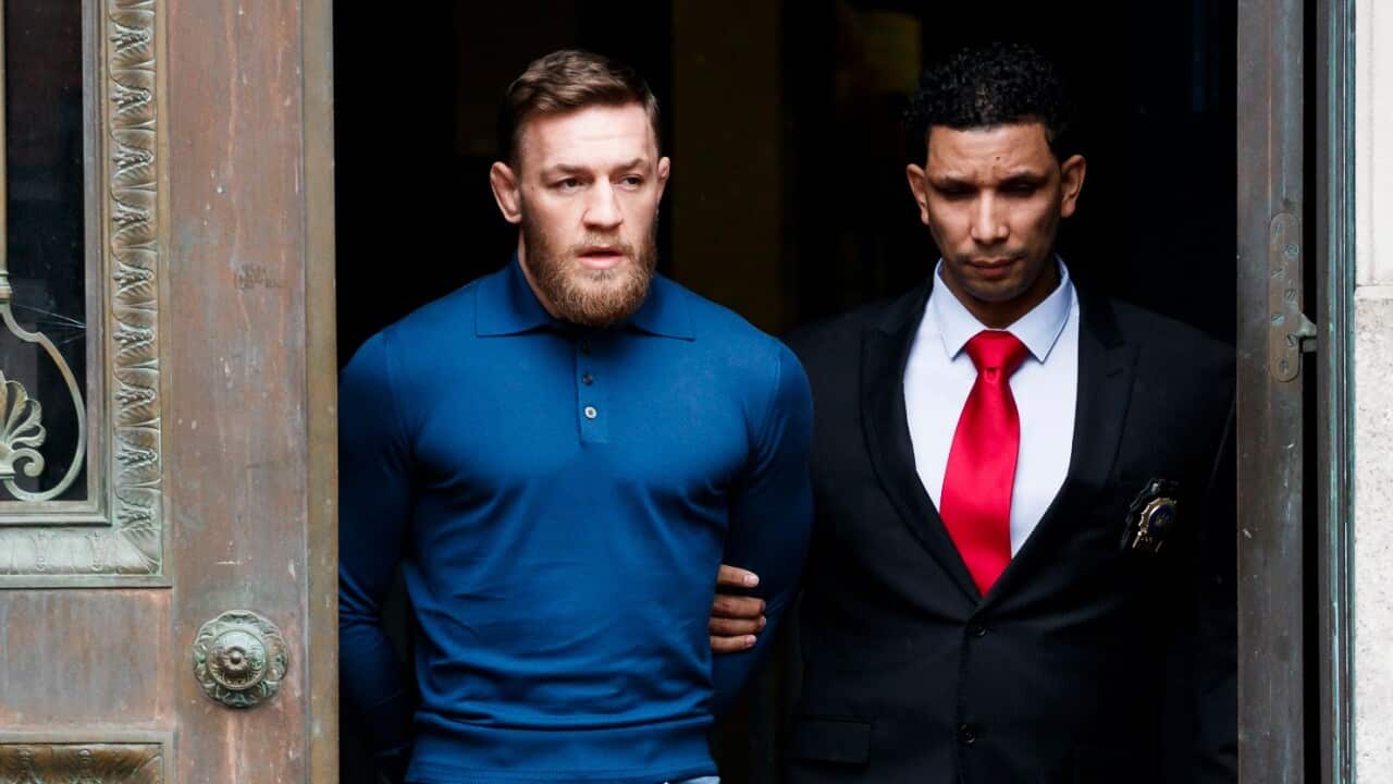 Mixed martial arts fighter Conor McGregor (L) is escorted from a New York City police precinct after he turned himself in