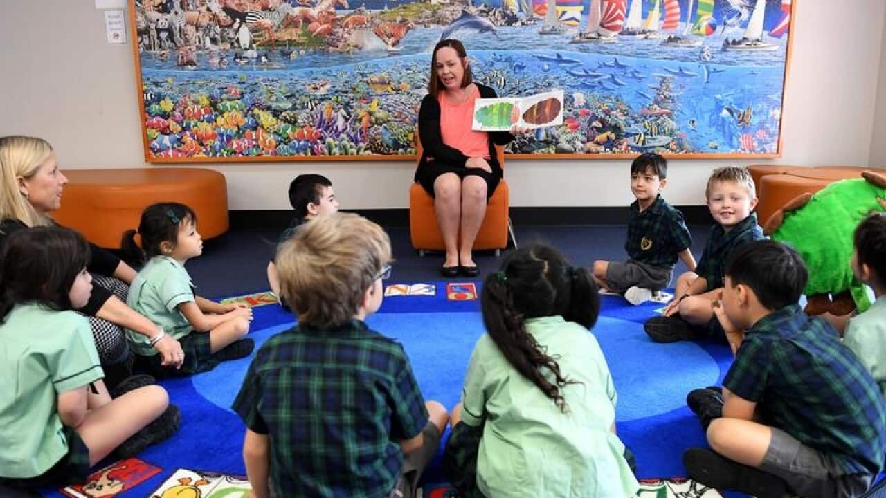 A teacher reads a story to young students