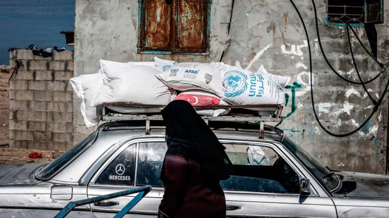 A woman walks past sacks of humanitarian aid provided by the United Nations Relief and Works Agency in Gaza City on February 21, 2021.