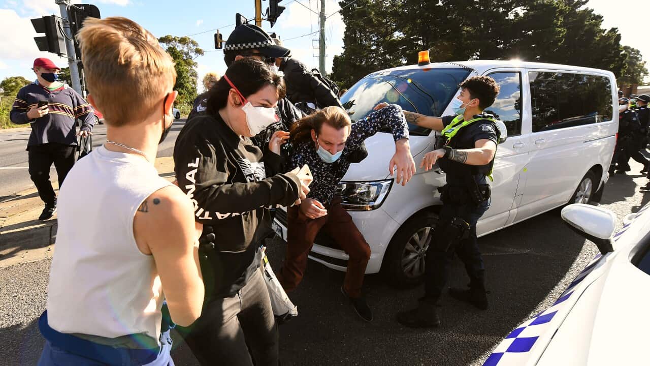 Protesters scuffle with Victorian Police officers in front of a white van
