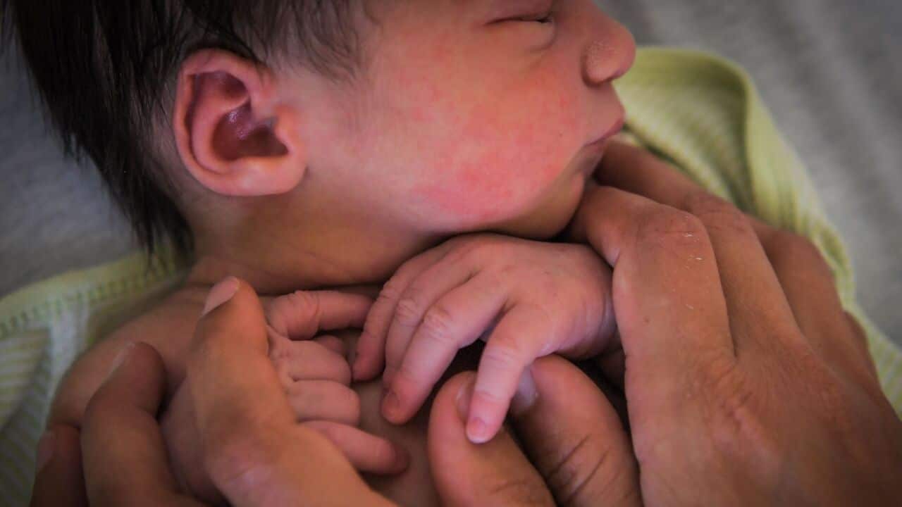 A mother holds her newborn baby