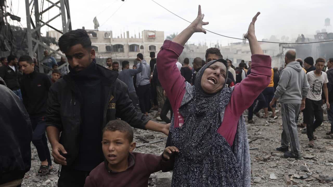 A woman with her hands raised with rubble around her