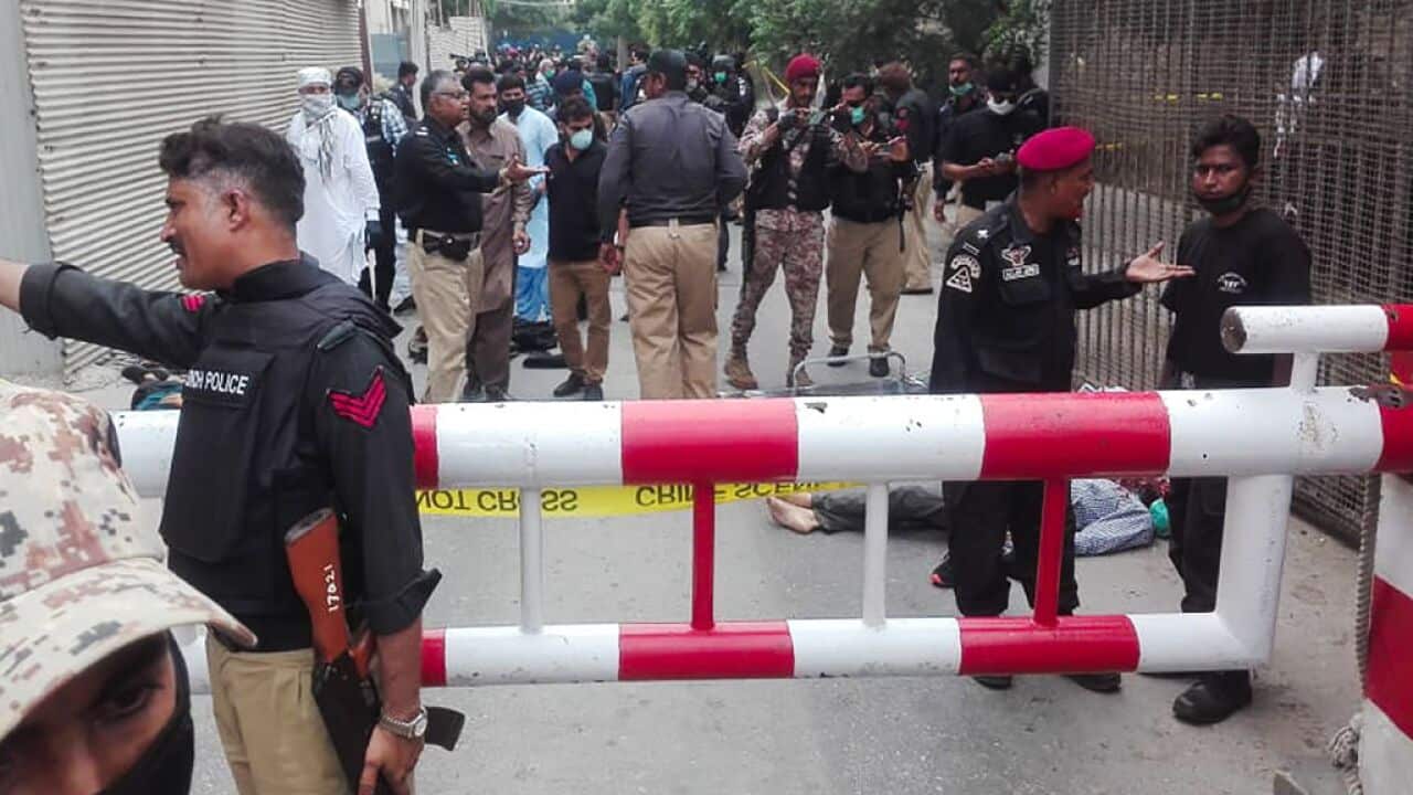 Policemen secure an area around a body outside the Pakistan Stock Exchange building after a group of gunmen attacked the building in Karachi.