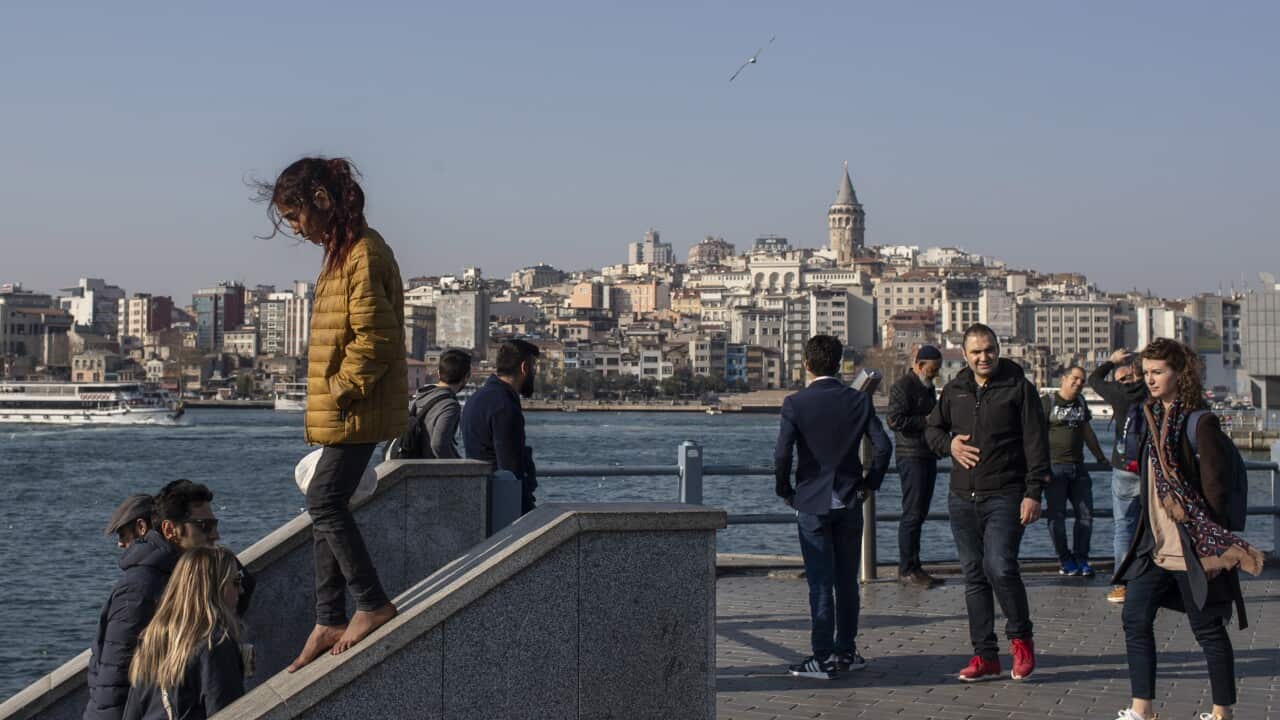 A Syrian refugee girl walks on the wall on a walkway situated near the Galata Tower on a sunny day in Istanbul