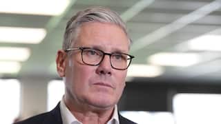 A tight shot of Keir Starmer wearing a black suit and black glasses