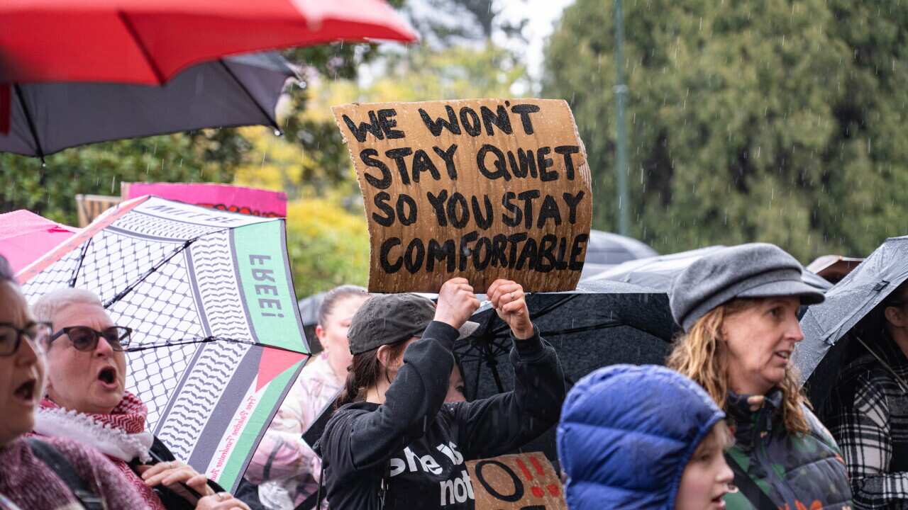 A protester holds a placard that says " We wont stay quiet