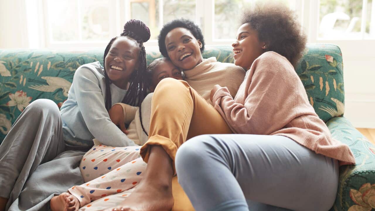 Portrait of happy woman embracing girls at home