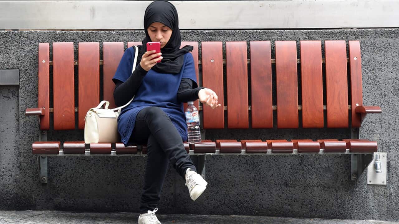 A woman of muslim appearance looks at her mobile phone in Brisbane