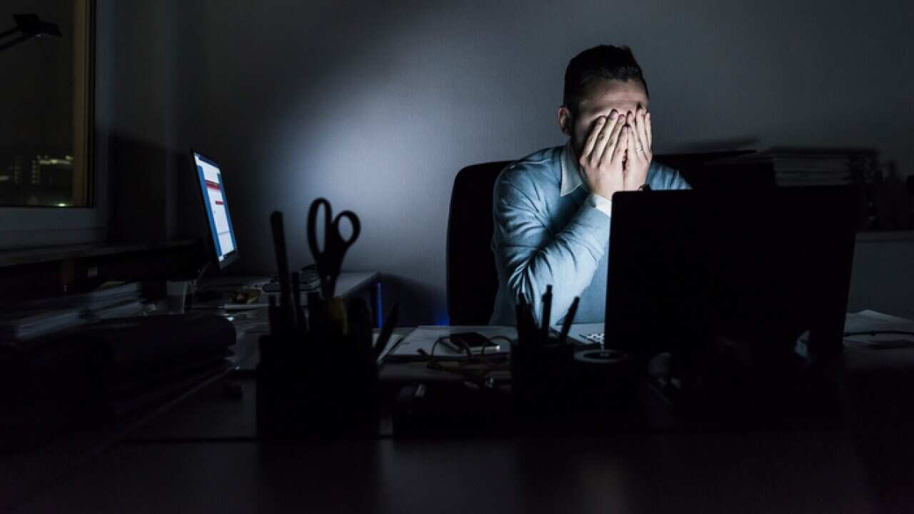 Exhausted businessman sitting at desk in office at night