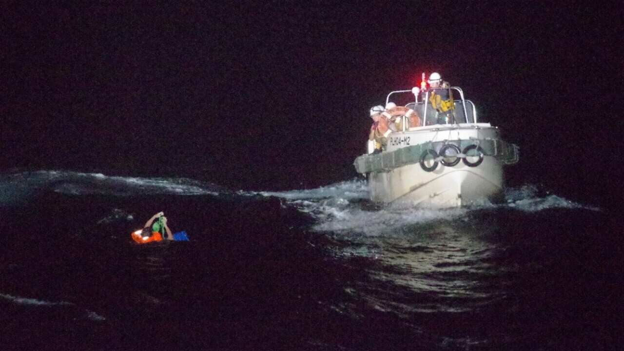 Japan Coast Guard officers rescuing a crew member of the stricken cargo vessel