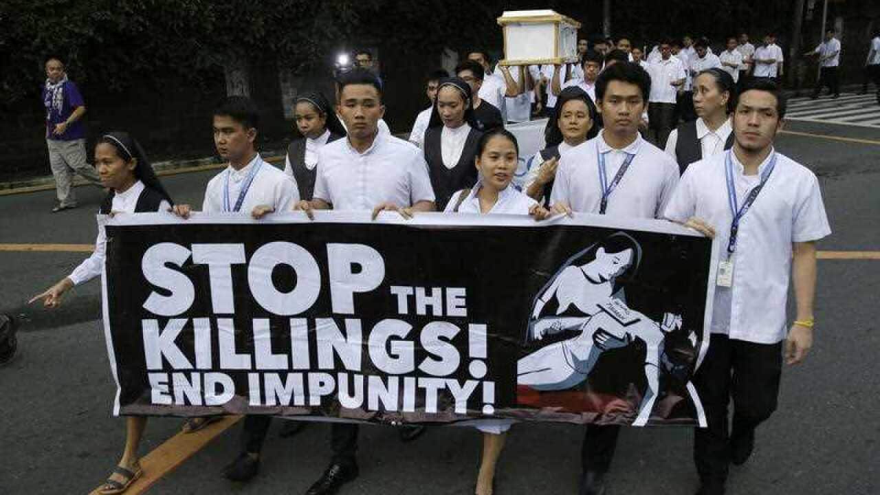 Seminarians and nuns carry slogans and a mock coffin during a rally in Manila, Philippines, against drug-related killings and martial law.