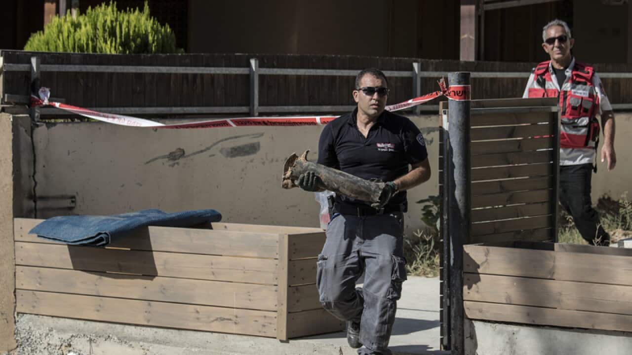 An Israeli police snapper carries part of a rocket in Sderot, Israel