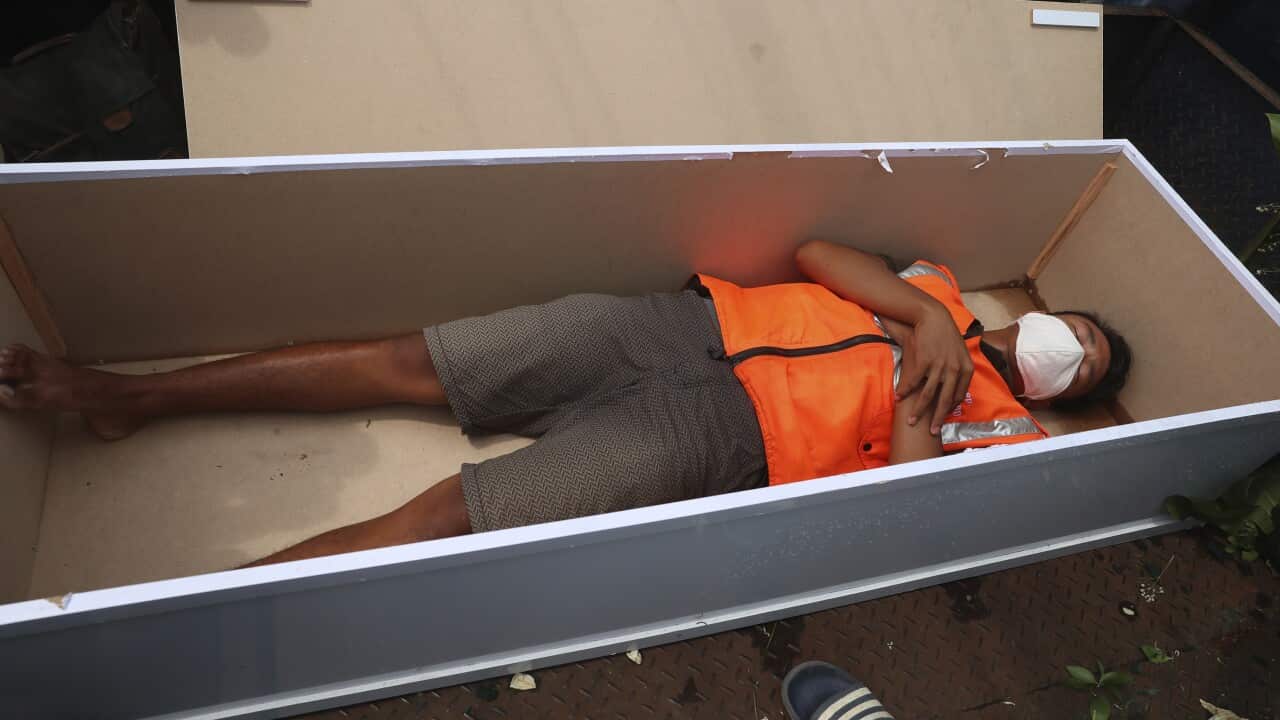 A man lays inside a mock coffin as punishment for violating regulations in Jakarta, Indonesia, requiring people to wear face masks in public places.