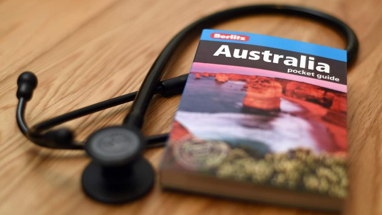 A doctor's stethoscope lies next to a guide book to Australia.