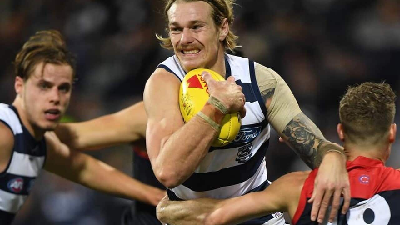 File image of Tom Stewart of the Cats being tackled by Demons players.