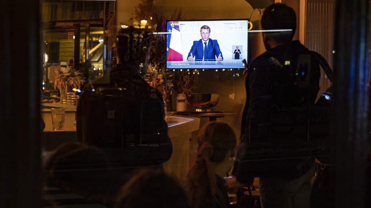 Customers in a cafe watch President Emmanuel Macron as he announces a lockdown