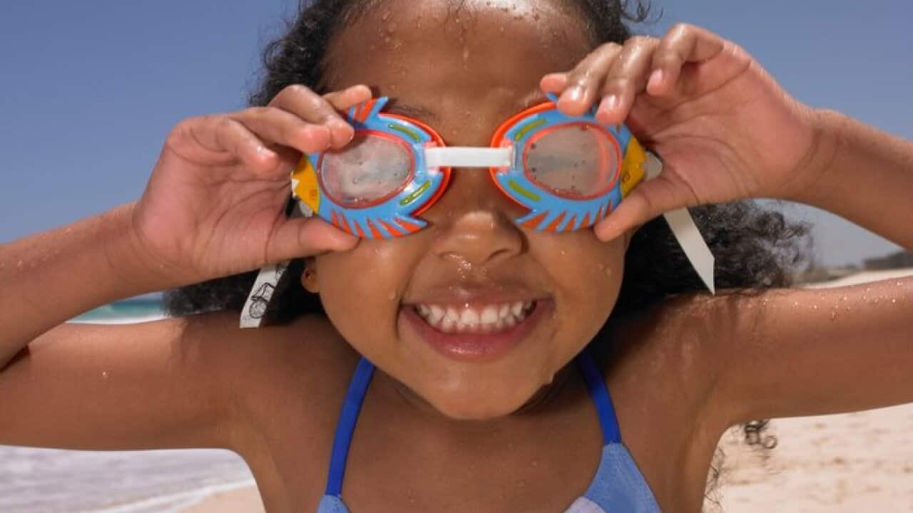 Smiling girl wearing goggles at beach