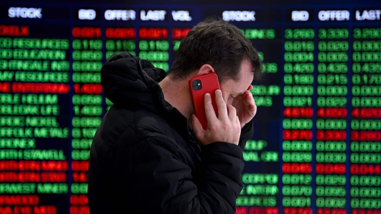 A person on the phone in front of indicator boards at the Australian Securities Exchange (ASX) in Sydney (AAP).jpg