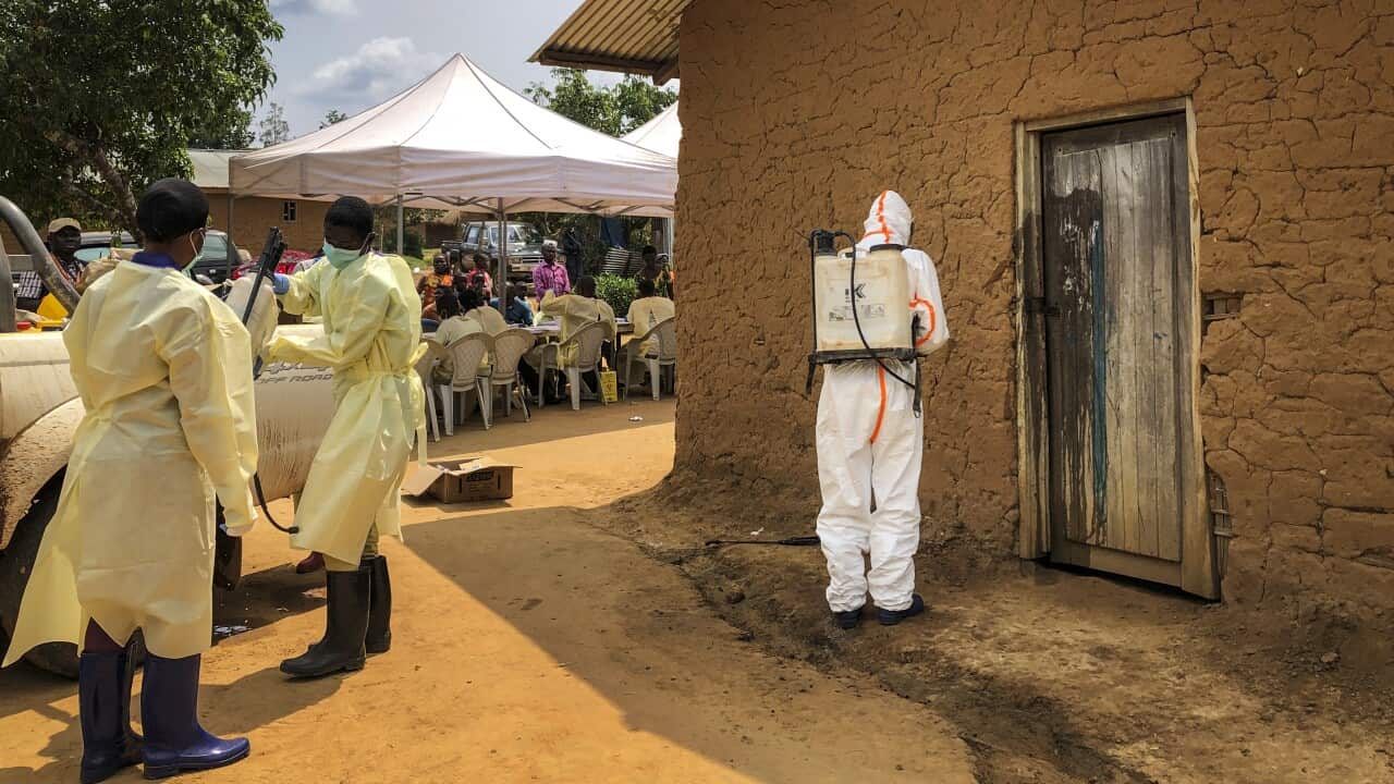 A worker from the World Health Organization decontaminates the doorway of a house on a plot where two cases of Ebola were found in eastern Congo.