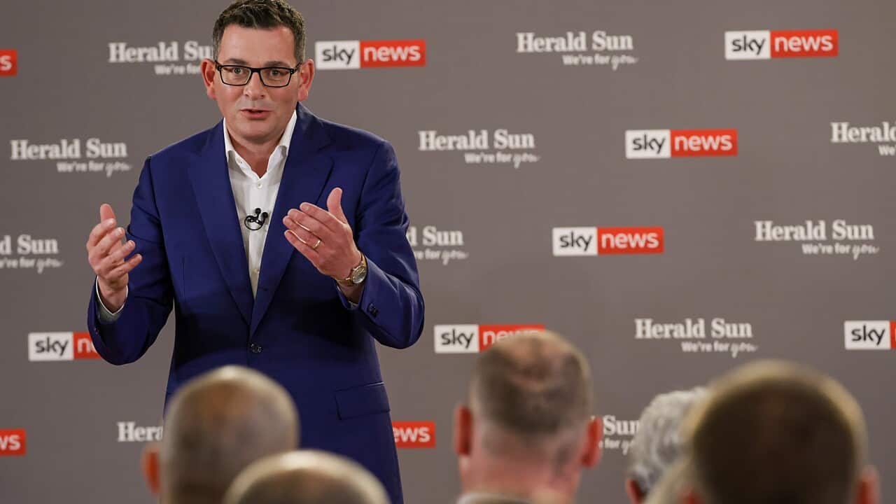 Dan Andrews gestures with his hands in front of an audience