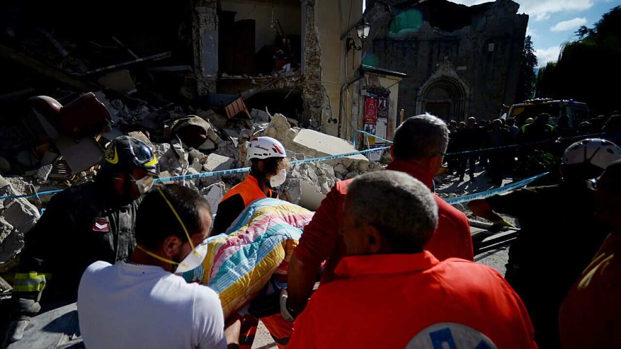 Rescuers carry the body of a victim in Amatrice on August 24, 2016 after a powerful earthquake rocked central Italy.