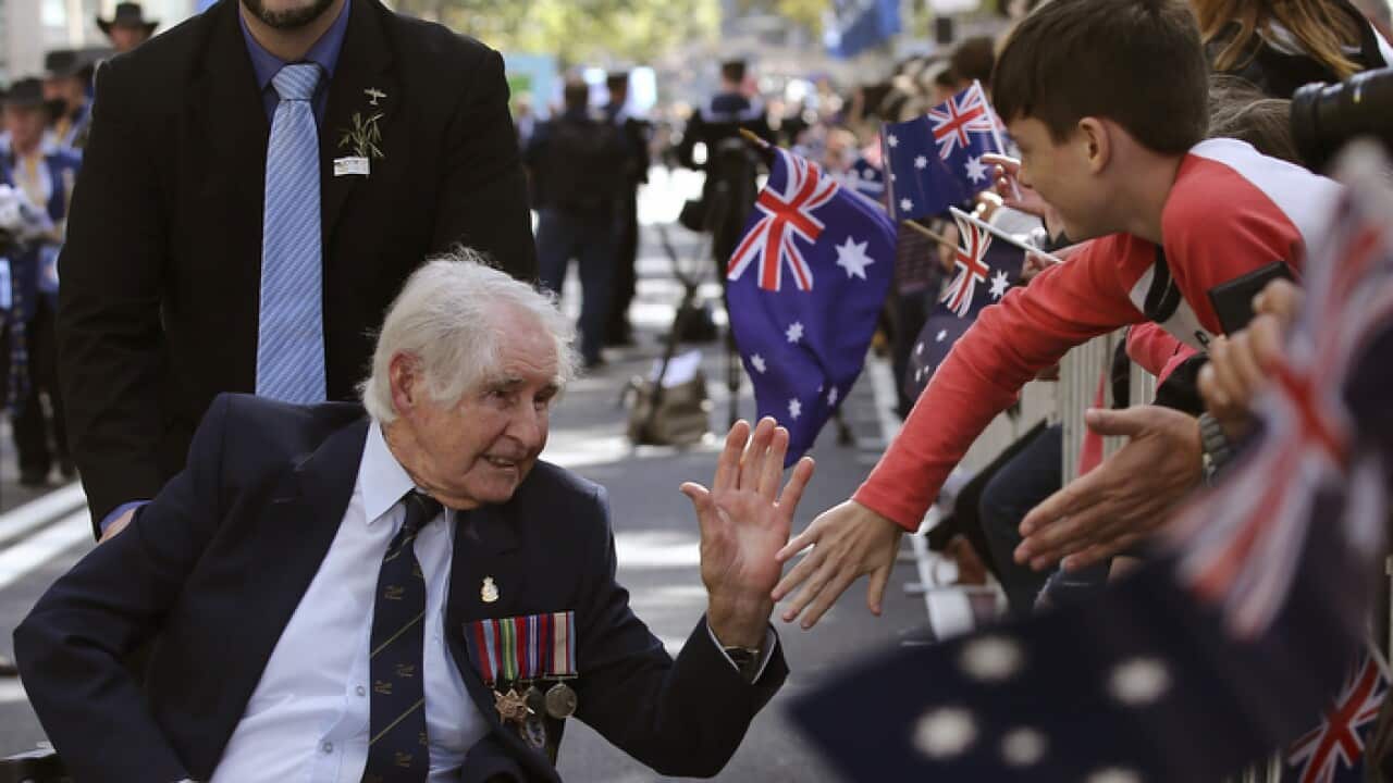 A war veteran gives a high five to a boy as he participates in the annual Australia and New Zealand Army Corps (ANZAC)