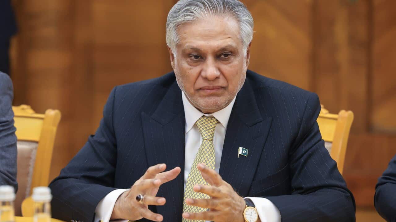 A man sits at a desk in a suit