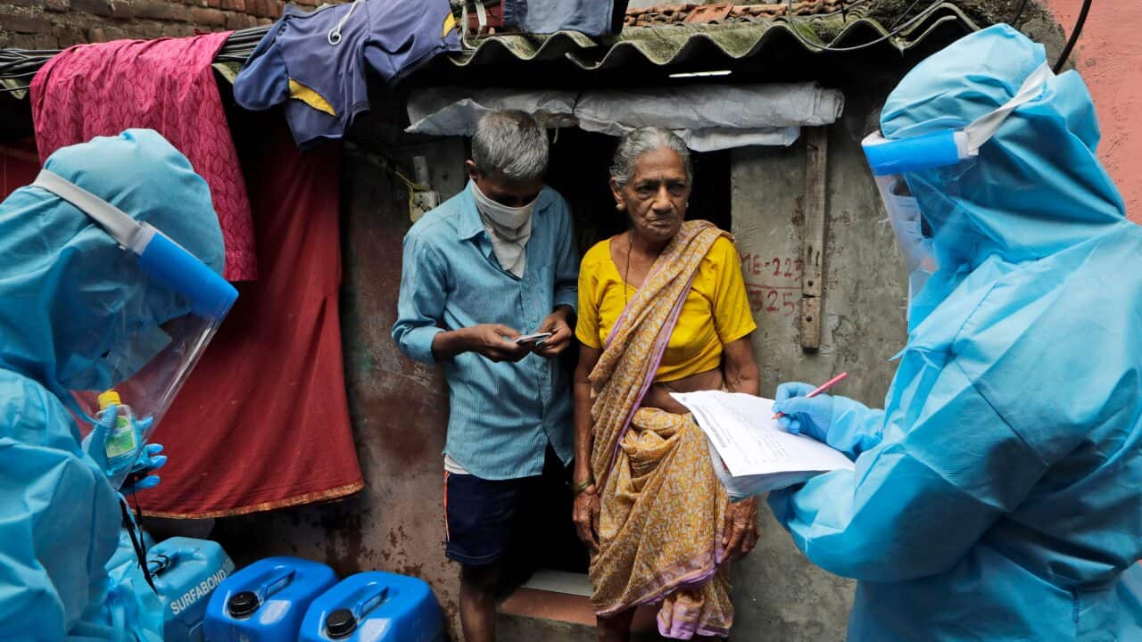 Health workers screen people for COVID-19 symptoms at Devnar slum in Mumbai, India.