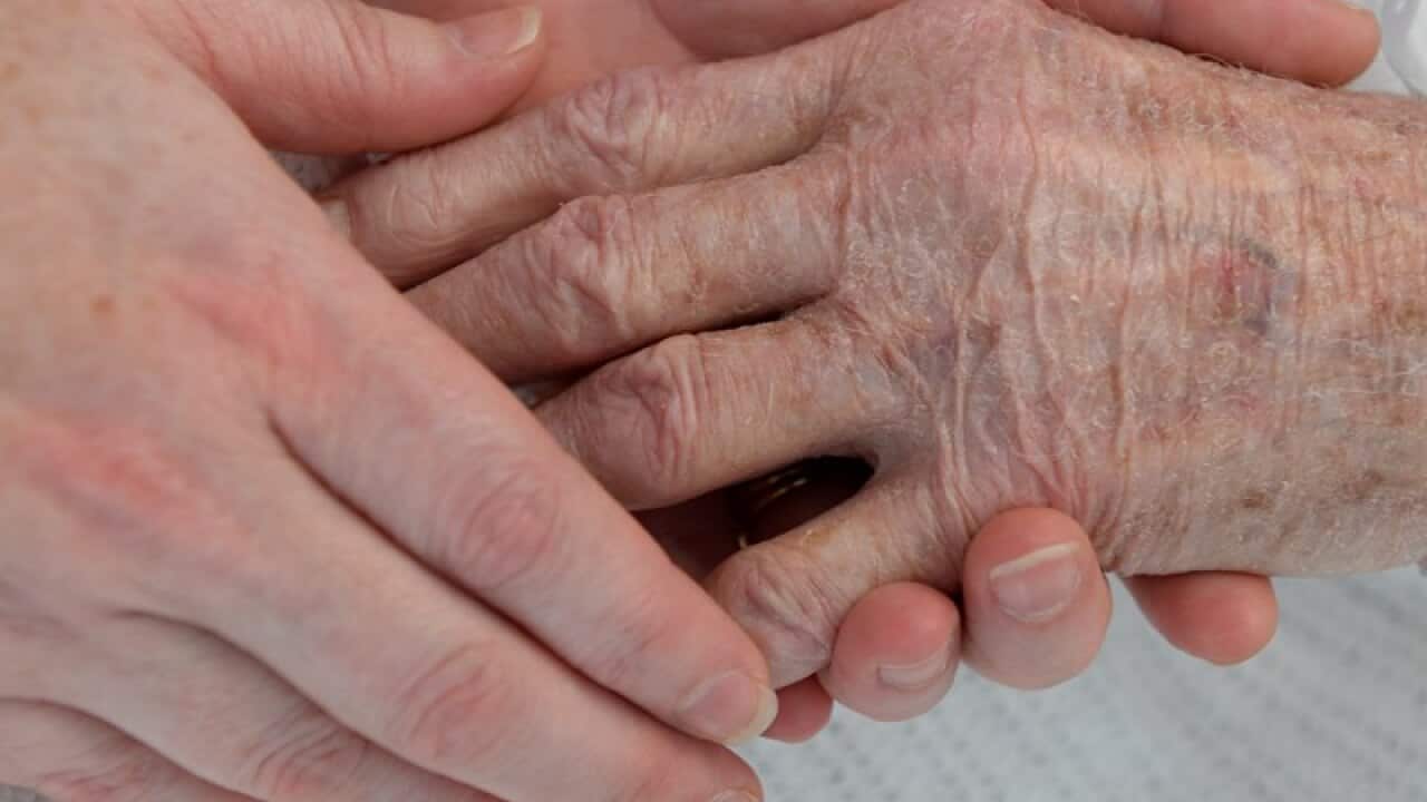 A nurse holds the hand of an elderly patient