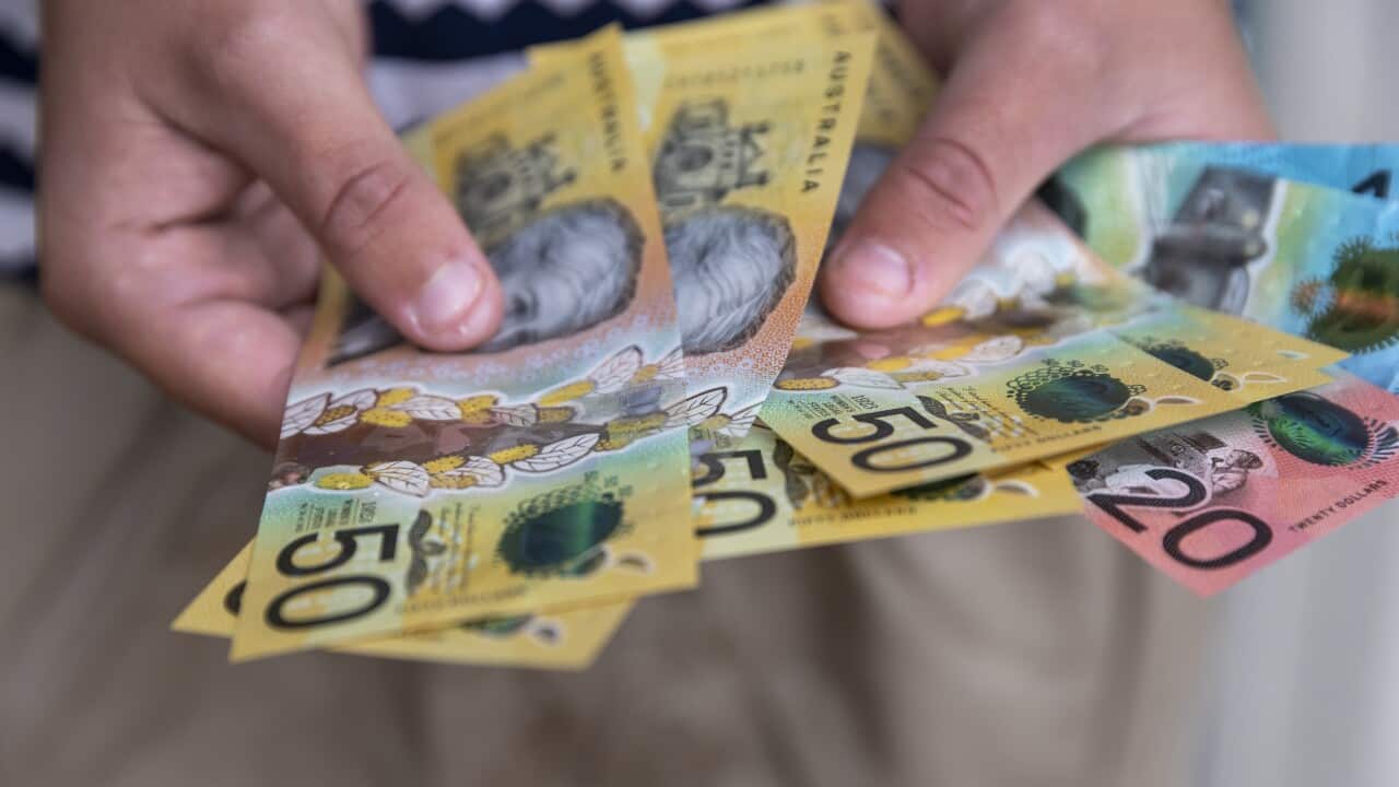Male person holding some Australian currency