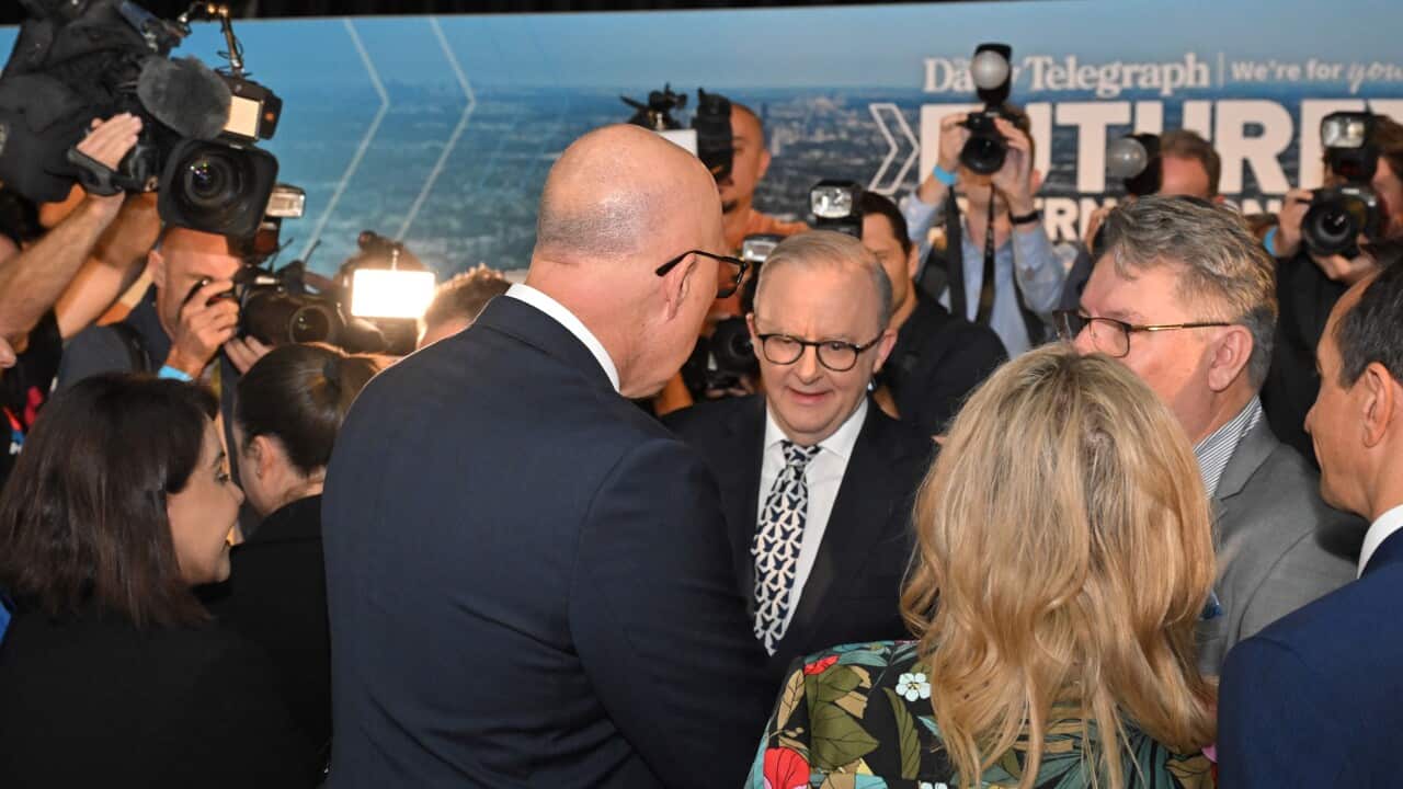Anthony Albanese and Peter Dutton face each other surrounded by camera operators and journalists.