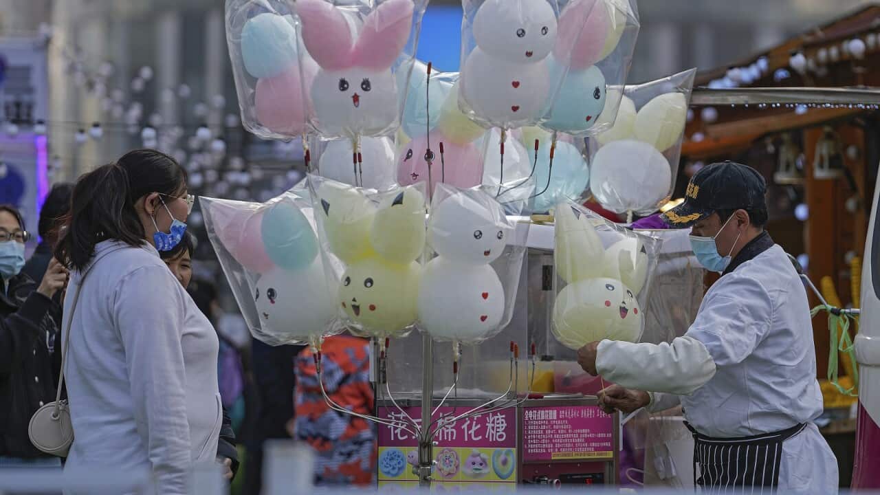 A vendor wearing a face mask to help protect from the coronavirus make cotton candy for his customers during a foods carnival at a shopping mall in Beijing, Sunday, Oct. 24, 2021. (AP Photo/Andy Wong)