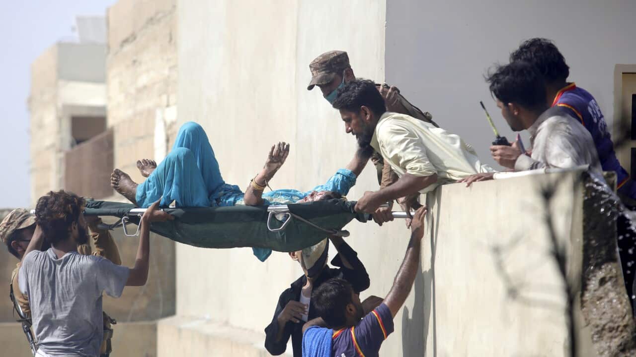Volunteers carry an injured person at the site of a plane crash in Karachi, Pakistan, Friday, May 22, 2020.