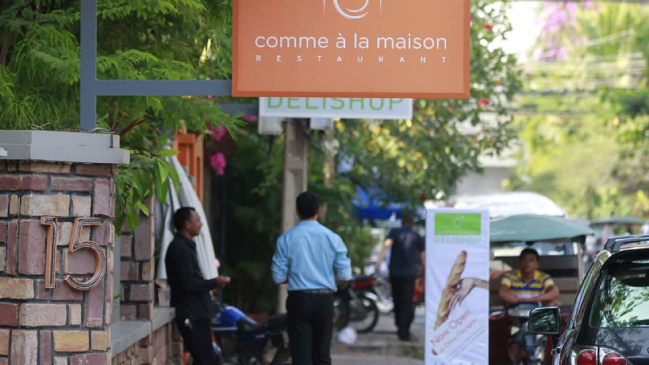Cambodians stand in front of a French restaurant in Phnom Penh