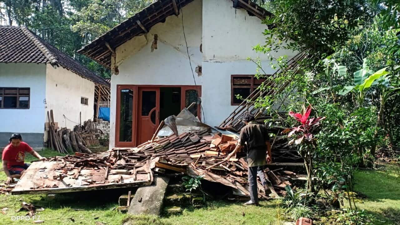 People inspect a collapsed house