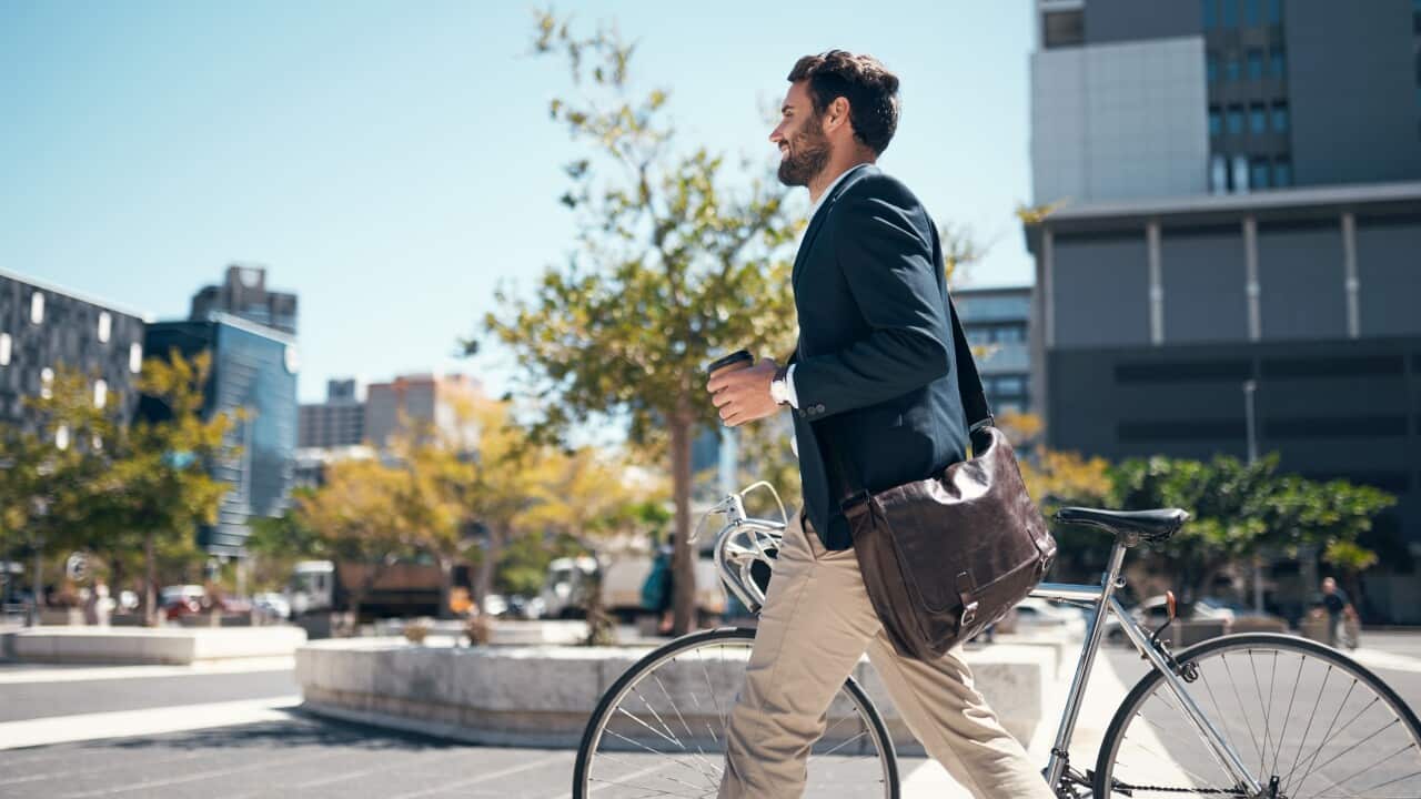 Shot of a young businessman traveling through the city with his bicycle