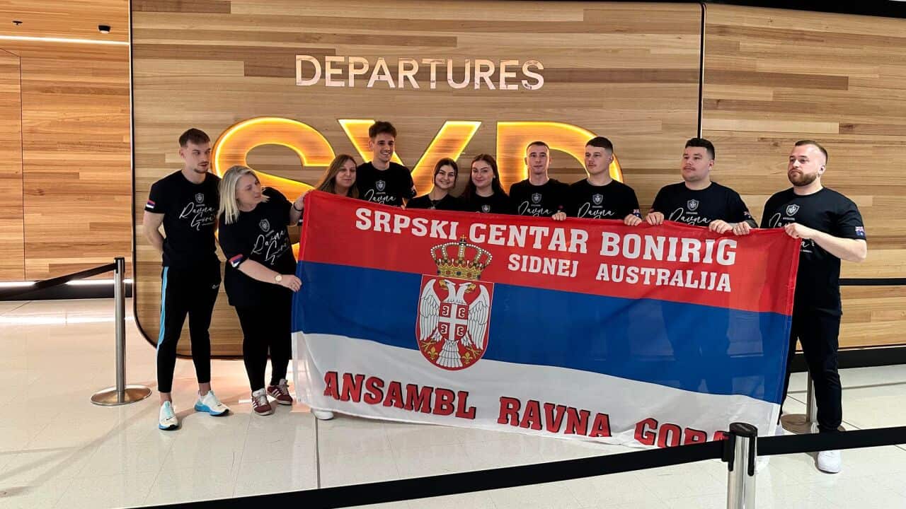 Members of the Ravna Gora Bonnyrigg folkloric ensemble poses with Serbian flag ahead of departure from Sydney airport to their 2023 Homeland Tour