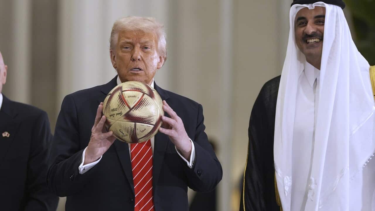 President Donald Trump handles a FIFA soccer ball as Qatar's Emir Sheikh Tamim bin Hamad Al Thani looks on (AAP)