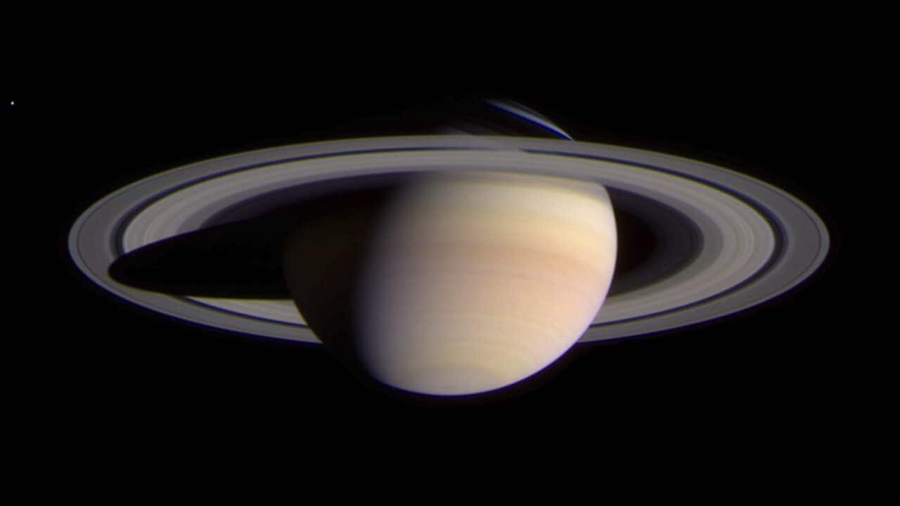 The planet Saturn as photographed by the Cassini spacecraft, appears against the dark, black space.