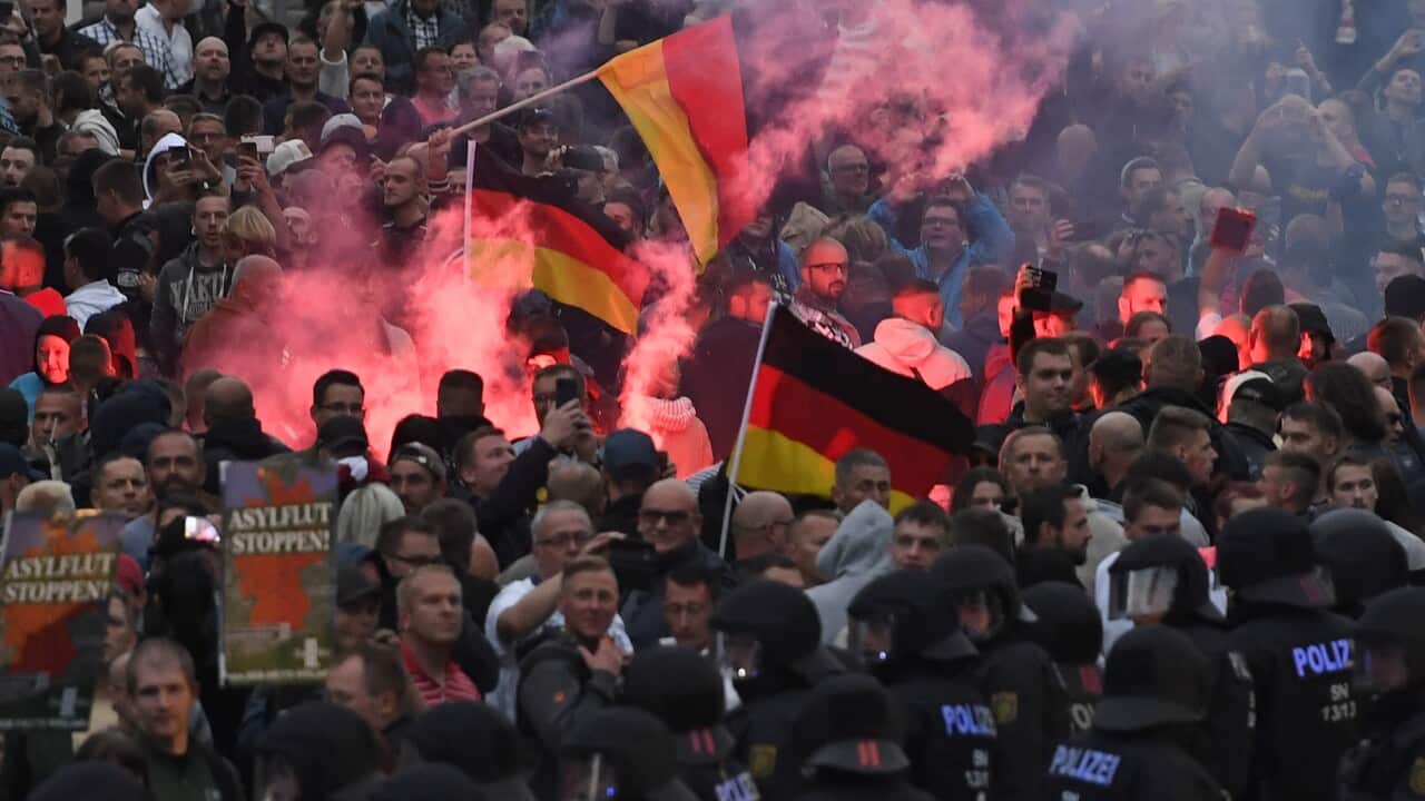 Right wing protesters light flares while facing police as they gather at the place where a man was stabbed in the night of the 25 August 2018